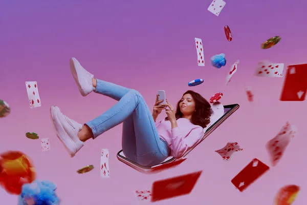 A young woman relaxing with her phone while dynamic casino elements float around her, illustrating the smooth mobile experience offered by the L85 app.