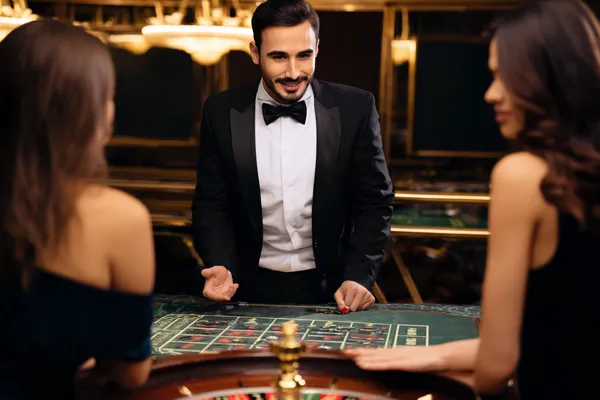 A professional dealer in a tuxedo greeting players at the roulette table, symbolizing the authentic live casino feel at L85.