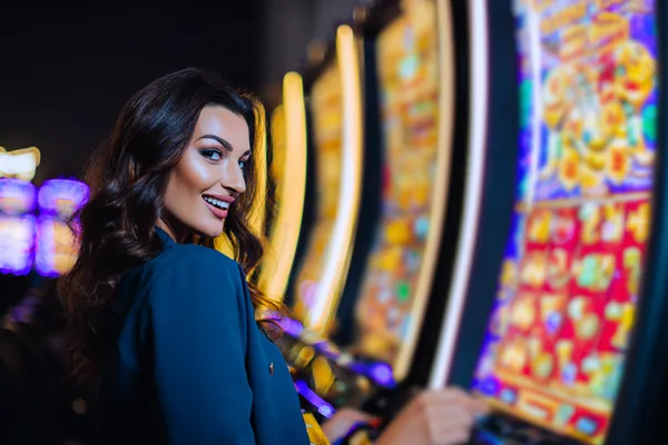 A woman smiling by bright slot machines showing lucky symbols, showcasing the exciting slot offerings at L85.
